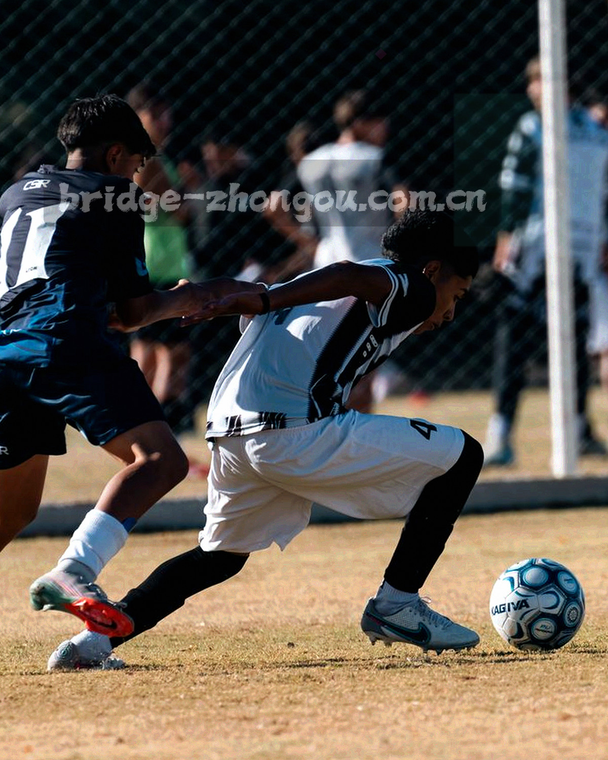 球员热身剪影，逆光近景裁切，只见腿部与球鞋动作